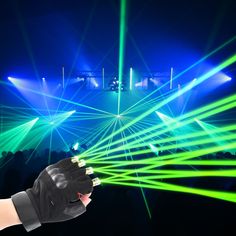 a person is holding their hand out to light up the stage with green and blue lights