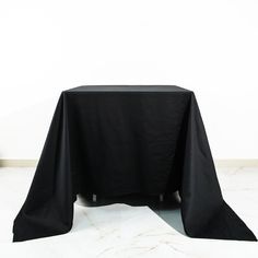 a black table cloth on top of a white table with an empty chair in the background