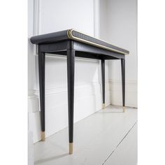 a black and gold console table sitting on top of a white floor next to a wall