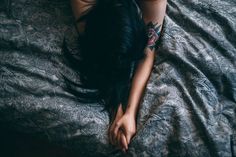 a woman laying on top of a bed covered in black feathers