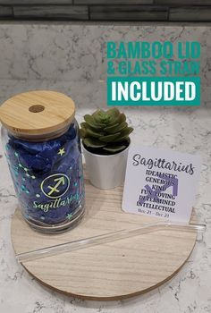 a bamboo lid and glass strainer is shown on a marble countertop next to a succulent plant