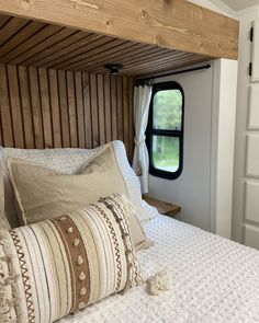 a bed with pillows and blankets in a small room next to a door that has a window