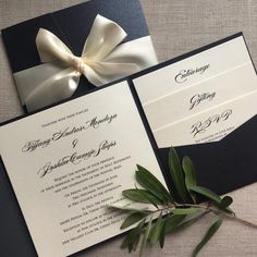 an elegant black and white wedding card with a bow on the front is laying on a table