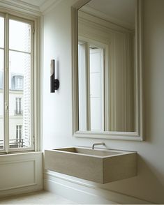 a bathroom sink sitting next to a window with a mirror on it's side