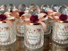 there are many glass jars with pink flowers on them and ribbons tied around the lids