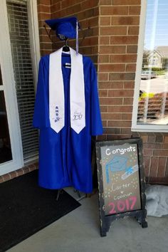 a graduation gown and cap are on display in front of a door with a sign