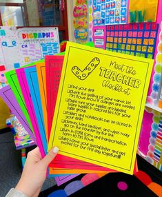 a person holding up a yellow sign in front of colorful bulletin boards with writing on them