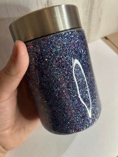 a hand holding a purple and blue glittered cup