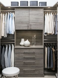 an organized closet with drawers and clothes hanging on the walls, along with a stool