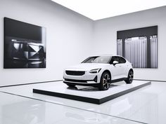 an electric car is on display in a white room with black and white pictures behind it