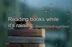 stack of books sitting on top of each other in front of a rain soaked window