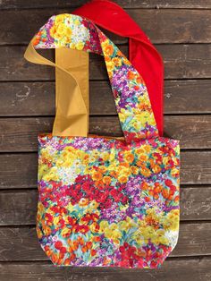 a colorful floral bag hanging on a wooden wall