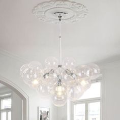 a chandelier hanging from the ceiling in a room with white walls and windows