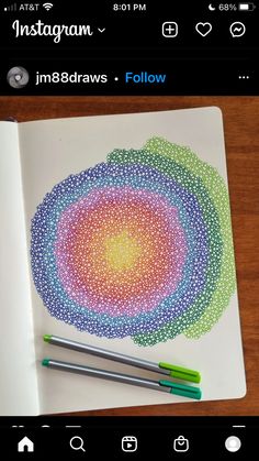 two pens are sitting on top of a notebook with an intricately designed circle in the middle