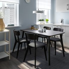 a dining table with four chairs and a clock on the wall above it in a kitchen