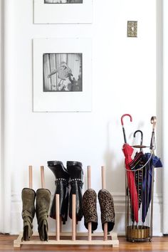 several pairs of boots and umbrellas are lined up on a shelf in front of a white wall