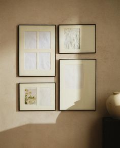 four framed pictures hang on the wall next to a vase