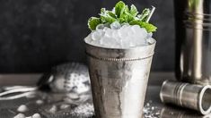 a silver cup filled with ice and mint sprinkled on top of a table