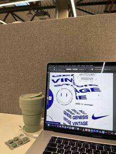 an open laptop computer sitting on top of a white desk next to a coffee cup