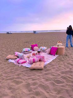 a blanket and pillows on the beach with people in the background