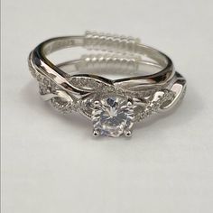 a white gold ring with an intricate design on the band and a round cut diamond in the center