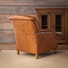 a brown leather chair sitting in front of a wooden cabinet