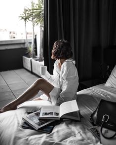 a woman sitting on top of a bed reading a book