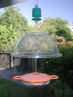 a bird feeder hanging from the side of a house with trees in the back ground