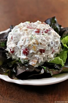 a white plate topped with salad on top of a wooden table