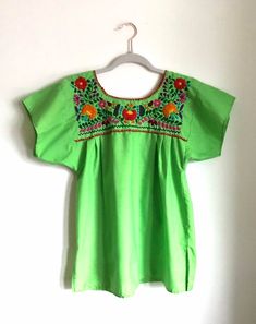 Beautiful vintage embroidered green, floral, Mexican blouse. The Mexican top is a beautiful green with brightly embroidered flowers on the front and back of the shirt.The blouse is lightweight and comfortable, perfect for the summer. It is made of 80% cotton and 20% polyester. The top is made in Mexico El Rebezo and is a size small.Please note a faint stain in the images and leather belt in not included.All items sold As Is. Any questions or concerns please contact me. Summer Green Blouse With Crew Neck, Green Crew Neck Blouse For Spring, Green Crew Neck Blouse For Summer, Green Floral Embroidered Crew Neck Blouse, Green Crew Neck Blouse With Floral Embroidery, Green Embroidered Crew Neck Blouse, Green Short Sleeve Summer Blouse, Spring Embroidered Green Blouse, Light Green Short Sleeve Tops For Spring