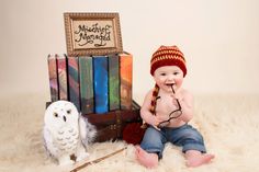 a baby sitting next to an owl and some books