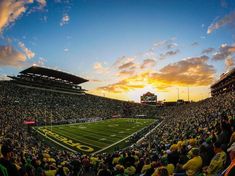 a football stadium filled with lots of people watching the sun go down on it's field