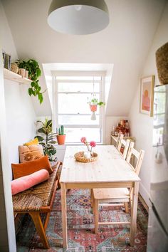 a room with a table, chairs and plants in the window sill on the wall