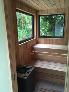 an empty sauna with two windows on each side and a trash can in the middle