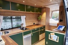 the interior of a camper with wood paneling and green cabinets, including a laptop computer