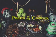 a table topped with lots of different foods and desserts covered in fake skulls next to the words pirates of the caribbean