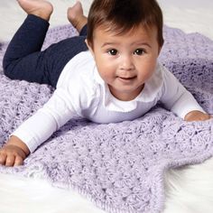 a baby laying on top of a purple blanket