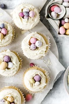 several cupcakes with white frosting and decorated eggs