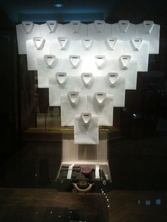 a display case with several pieces of clothing hanging on it's sides and lights in the background