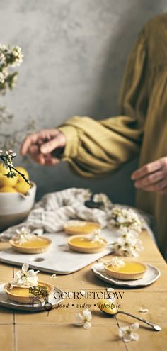 two people standing at a table with plates and bowls of food on it, one person reaching for the plate