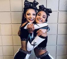 two women in black and white outfits hugging each other with their arms around one another