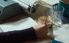 a person writing on a piece of paper with a cup of coffee in front of them