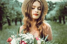 a woman in a hat holding a bouquet of flowers