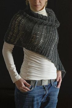 a woman standing with her hands on her hips wearing a gray knitted shawl