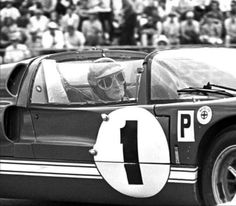 a black and white photo of a man driving a race car with the number 1 on it