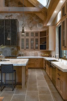 a large kitchen with wooden cabinets and marble counter tops, along with an island in the middle