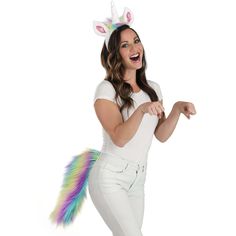 a woman in white pants and a unicorn hat is posing with her hands out to the side