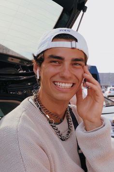 a young man smiles while talking on his cell phone in the back of a car