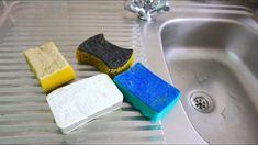 three sponges sitting on top of a sink next to a blue and yellow rag