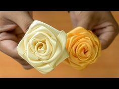 two hands holding small yellow and orange flowers